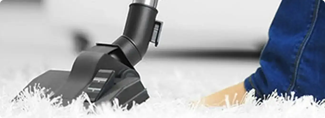 Close-up of a professional vacuuming a white carpet in Drake.