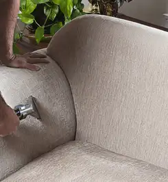 Professional upholstery cleaner deep-cleaning a fabric sofa with a handheld extraction tool and hose Fort Collins, CO.